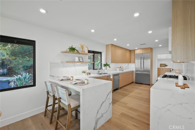 2115 E Santiago St, Covina, CA 91724 - kitchen with appliances with stainless steel finishes, a peninsula, open shelves, light stone countertops, and light wood-type flooring