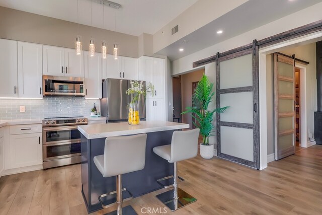 488 E Ocean Blvd Unit 502, Long Beach, CA 90802 - kitchen featuring stainless steel appliances, light wood-type flooring, light countertops, a barn door, and tasteful backsplash
