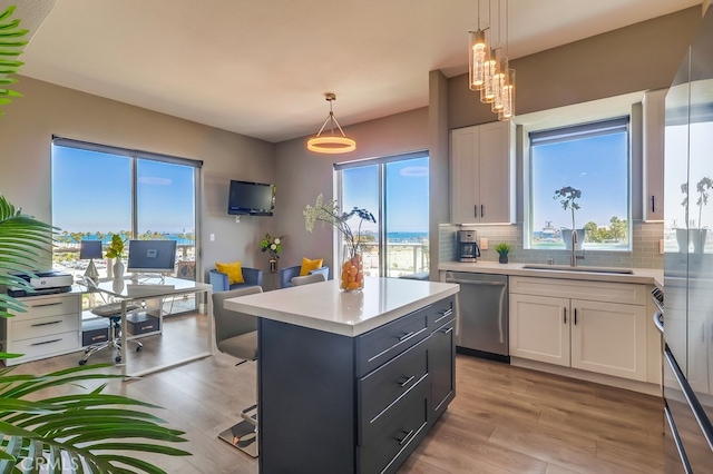 488 E Ocean Blvd Unit 502, Long Beach, CA 90802 - kitchen with stainless steel dishwasher, white cabinets, light countertops, backsplash, and light wood-style floors