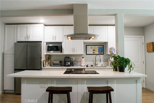 542 N Kilkea Dr, Los Angeles, CA 90048 - kitchen featuring appliances with stainless steel finishes, white cabinetry, island range hood, light wood-style floors, and a kitchen breakfast bar
