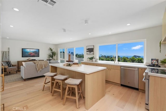 317 Calle Familia, San Clemente, CA 92672 - kitchen featuring stainless steel dishwasher, white range oven, light wood-style flooring, a breakfast bar area, and a kitchen island
