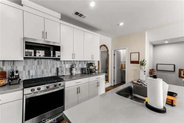 1206 W Cara Dr, Anaheim, CA 92805 - kitchen with appliances with stainless steel finishes, decorative backsplash, white cabinets, wood finished floors, and recessed lighting