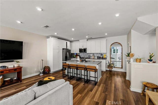 1206 W Cara Dr, Anaheim, CA 92805 - kitchen featuring stainless steel appliances, an island with sink, a kitchen bar, dark wood-style floors, and white cabinetry