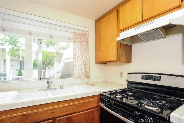 3342 Darby St Unit 317, Simi Valley, CA 93063 - kitchen with stainless steel gas range oven, under cabinet range hood, brown cabinetry, and tile counters