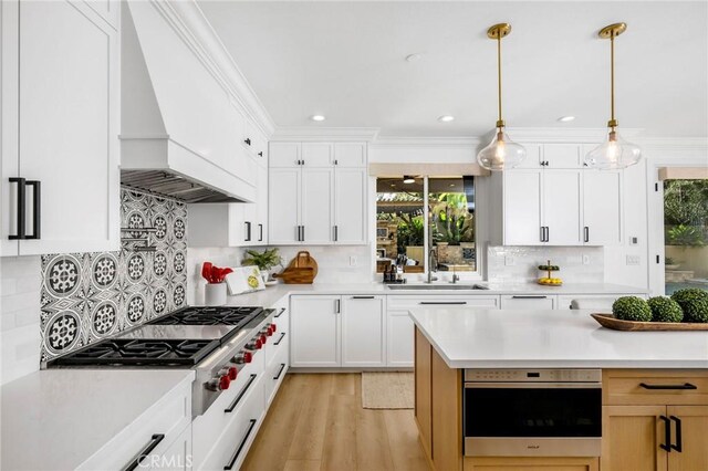 308 Via El Patio, San Clemente, CA 92673 - kitchen featuring appliances with stainless steel finishes, light countertops, tasteful backsplash, custom range hood, and hanging light fixtures