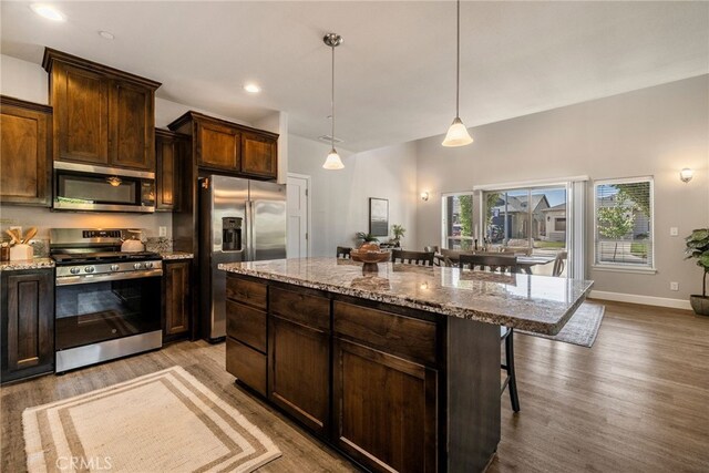 2740 Levi Ln, Chico, CA 95973 - kitchen with appliances with stainless steel finishes, a breakfast bar, light wood-type flooring, dark brown cabinets, and light stone countertops
