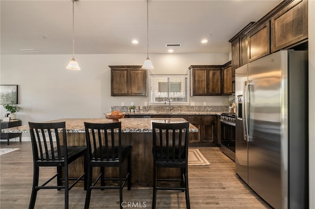 2740 Levi Ln, Chico, CA 95973 - kitchen featuring appliances with stainless steel finishes, dark brown cabinets, light stone countertops, a center island, and recessed lighting