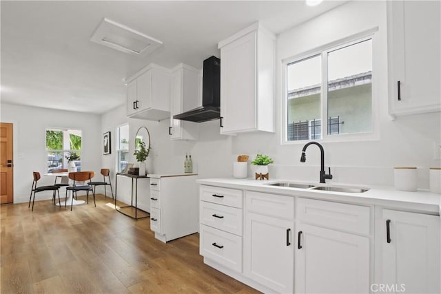 9525 Holmes Ave, Los Angeles, CA 90002 - kitchen with wall chimney range hood, white cabinetry, light countertops, and wood finished floors