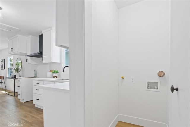 9525 Holmes Ave, Los Angeles, CA 90002 - kitchen featuring wall chimney range hood, white cabinetry, light wood-type flooring, and light countertops
