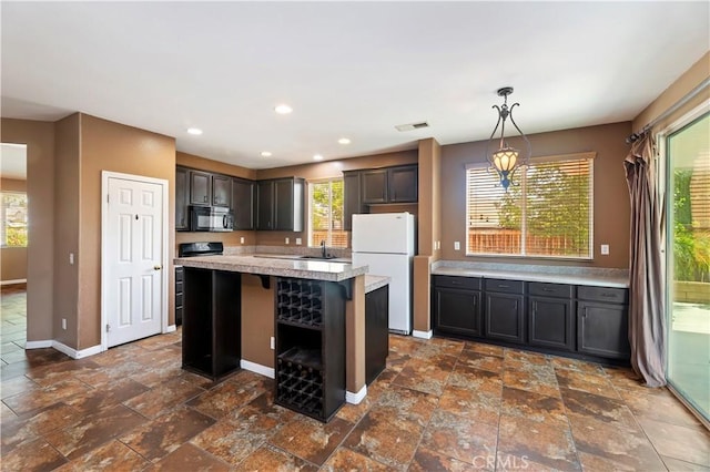 31139 Little Camille Way, Menifee, CA 92584 - kitchen featuring black microwave, freestanding refrigerator, stone tile floors, light countertops, and a center island
