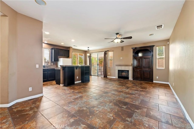 31139 Little Camille Way, Menifee, CA 92584 - unfurnished living room featuring a ceiling fan, recessed lighting, a tiled fireplace, and stone tile flooring