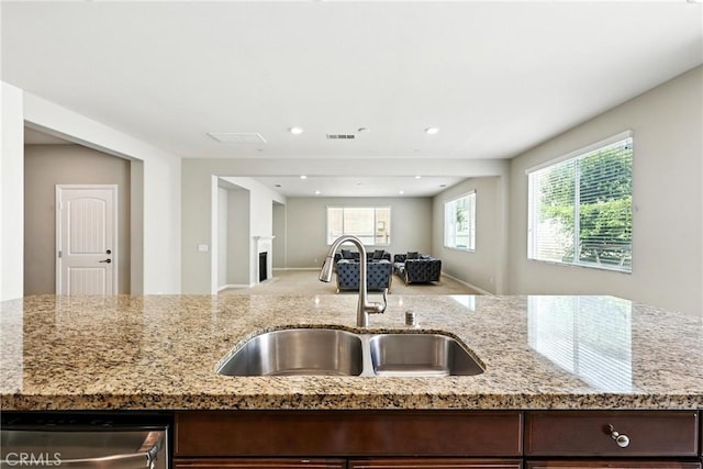 6212 Athena St, Chino, CA 91710 - kitchen featuring stainless steel dishwasher, open floor plan, light stone countertops, a fireplace, and dark brown cabinets