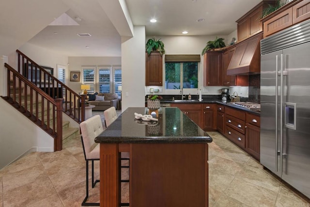 674 Calypso Pl, Encinitas, CA 92024 - kitchen featuring stainless steel built in fridge, a center island, dark stone counters, a kitchen breakfast bar, and plenty of natural light
