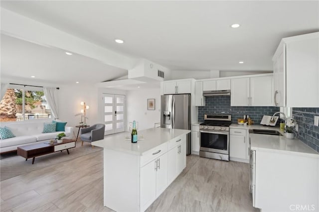 845 W Gateway Dr, Palm Springs, CA 92262 - kitchen featuring stainless steel appliances, under cabinet range hood, open floor plan, a center island, and decorative backsplash