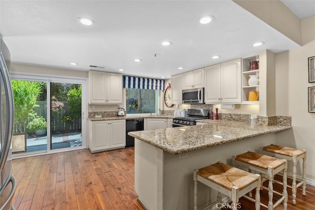 239 Via Presa, San Clemente, CA 92672 - kitchen featuring appliances with stainless steel finishes, light wood-style floors, white cabinets, a peninsula, and light stone countertops