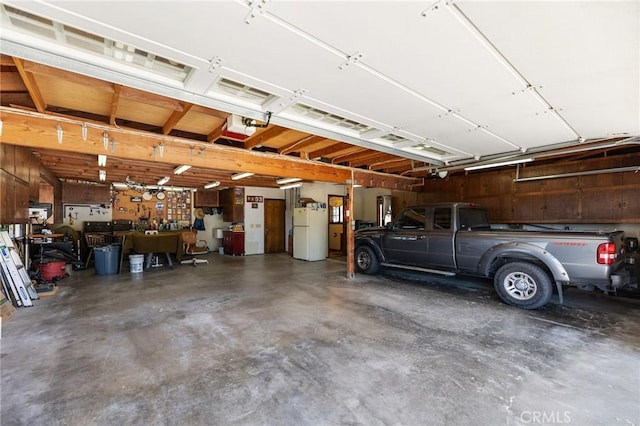 41050 Mesa Robles Cir, Temecula, CA 92592 - garage featuring freestanding refrigerator, a garage door opener, and a workshop area