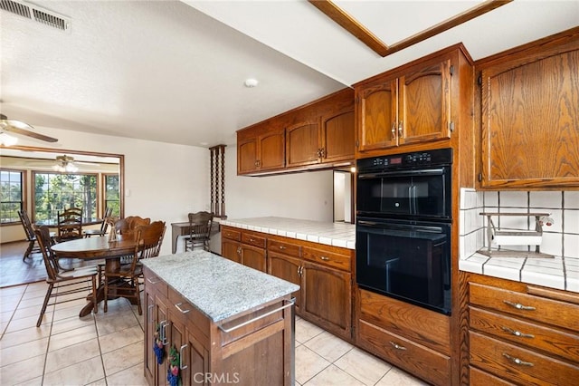 41050 Mesa Robles Cir, Temecula, CA 92592 - kitchen featuring a ceiling fan, light tile patterned floors, brown cabinets, and backsplash
