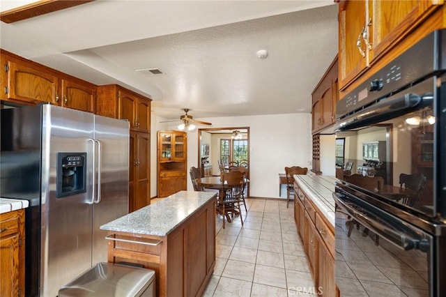 41050 Mesa Robles Cir, Temecula, CA 92592 - kitchen with stainless steel fridge with ice dispenser, brown cabinets, ceiling fan, and a center island