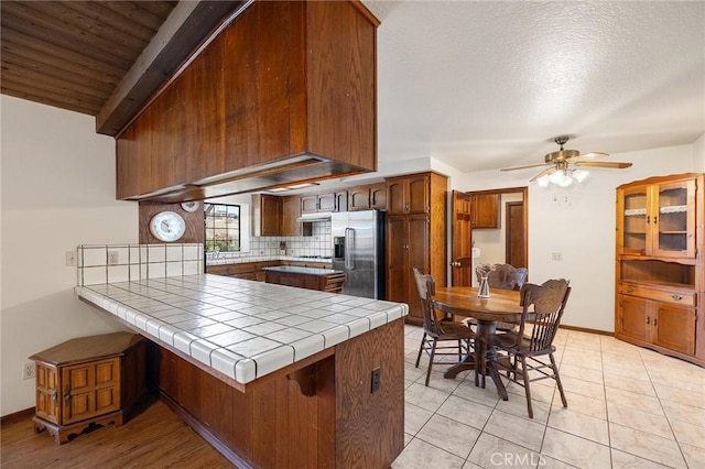 41050 Mesa Robles Cir, Temecula, CA 92592 - kitchen with stainless steel fridge with ice dispenser, a peninsula, backsplash, ceiling fan, and tile countertops