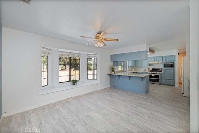 50128 Deer Meadow Way, Oakhurst, CA 93644 - kitchen with stainless steel appliances, a peninsula, a kitchen breakfast bar, blue cabinetry, and light wood-style flooring