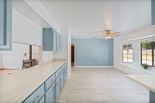 50128 Deer Meadow Way, Oakhurst, CA 93644 - kitchen featuring blue cabinets, light wood-style floors, ceiling fan, light countertops, and a wood stove