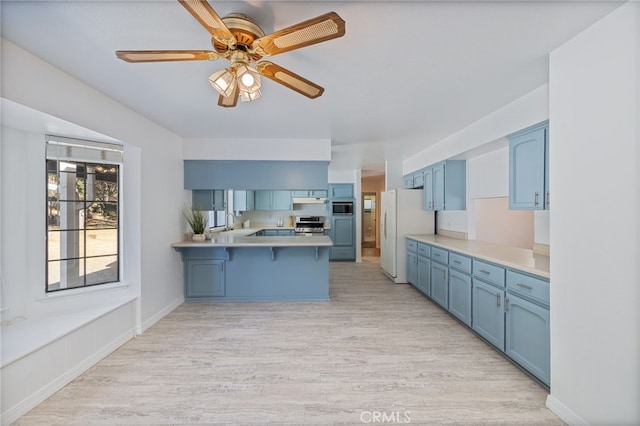 50128 Deer Meadow Way, Oakhurst, CA 93644 - kitchen featuring blue cabinets, a peninsula, freestanding refrigerator, a kitchen breakfast bar, and ceiling fan