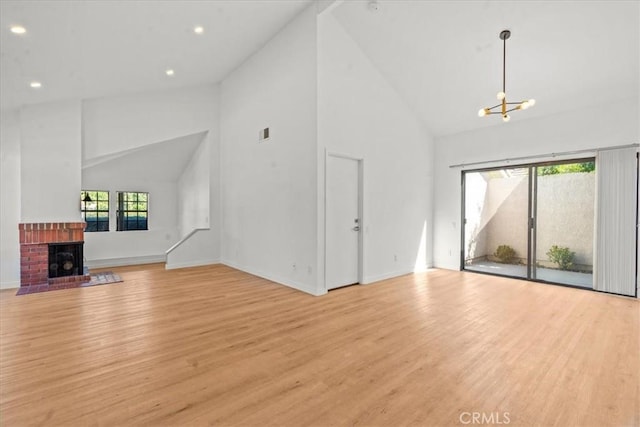 2 Brookstone, Irvine, CA 92604 - unfurnished living room with light wood finished floors, high vaulted ceiling, a chandelier, recessed lighting, and a fireplace