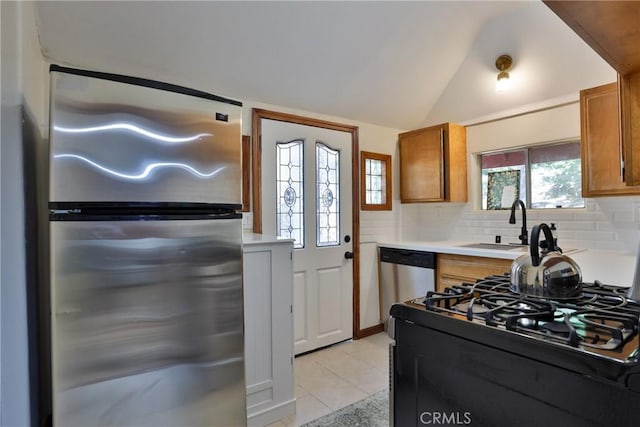 2548 Secret Dr, Running Springs, CA 92382 - kitchen with appliances with stainless steel finishes, light tile patterned floors, light countertops, brown cabinetry, and vaulted ceiling