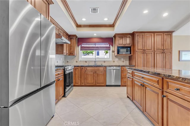 20002 Tomlee Ave, Torrance, CA 90503 - kitchen with stainless steel appliances, under cabinet range hood, a raised ceiling, dark stone countertops, and brown cabinets