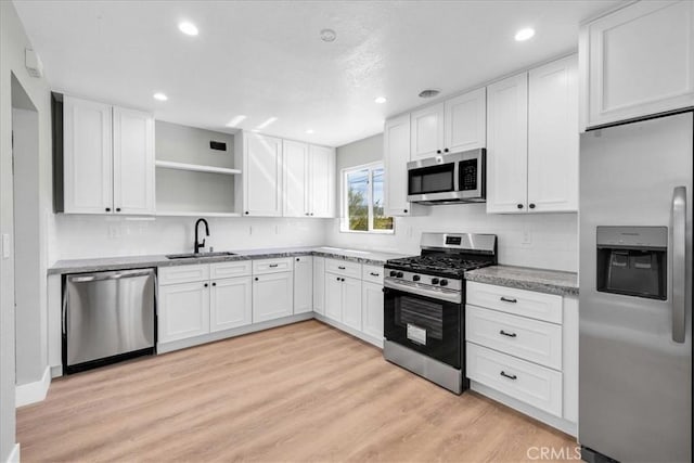 73461 El Paseo Dr Unit 29, Palms, CA 92277 - kitchen featuring appliances with stainless steel finishes, open shelves, white cabinets, light wood finished floors, and recessed lighting