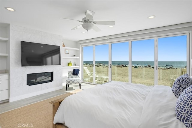 3312 W Oceanfront, Newport Beach, CA 92663 - bedroom featuring a water view, a fireplace, recessed lighting, wood finished floors, and ceiling fan