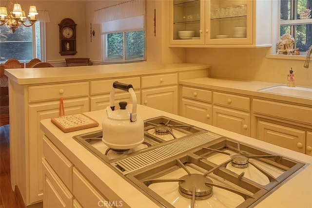 211 Heliotrope Dr, Lake Arrowhead, CA 92352 - detailed view of light countertops, glass insert cabinets, a chandelier, a peninsula, and pendant lighting