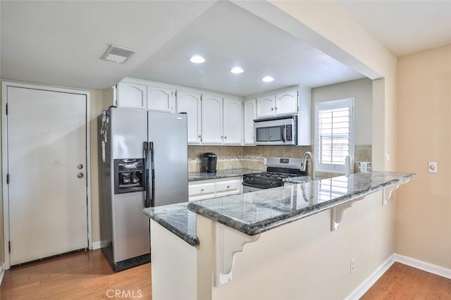 8366 Gabriel Dr Unit D, Rancho Cucamonga, CA 91730 - kitchen featuring appliances with stainless steel finishes, dark stone counters, a peninsula, light wood-style flooring, and recessed lighting
