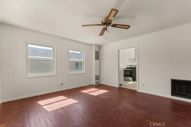 1550 Kaufman Ave, Corning, CA 96021 - unfurnished living room featuring a textured ceiling, a heating unit, hardwood / wood-style floors, a glass covered fireplace, and a ceiling fan