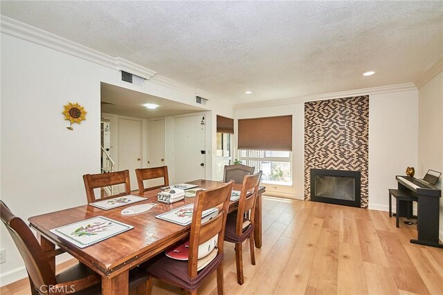 5574 Elsinore Ave, Buena Park, CA 90621 - dining area featuring ornamental molding, a textured ceiling, a tile fireplace, light wood-style floors, and recessed lighting