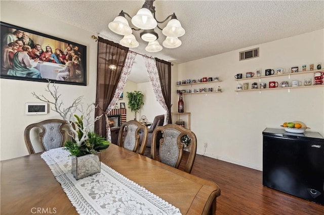 37158 29th St E, Palmdale, CA 93550 - dining space with a chandelier, wood finished floors, a textured ceiling, and a brick fireplace