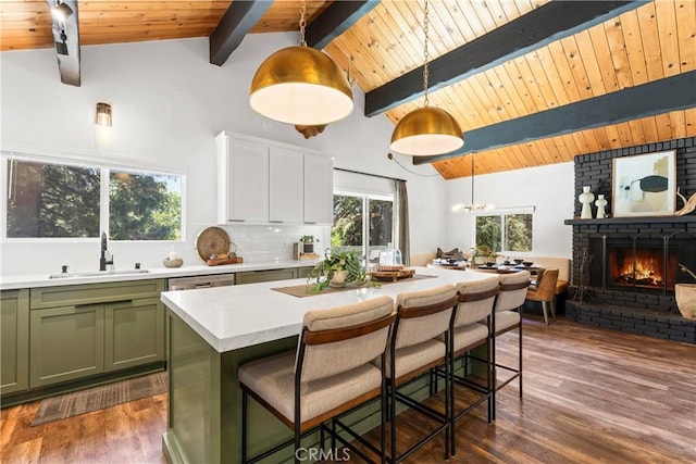 1016 Berne Dr, Crestline, CA 92325 - kitchen featuring green cabinetry, light countertops, a wood ceiling with exposed beams, dark wood-style floors, and a brick fireplace