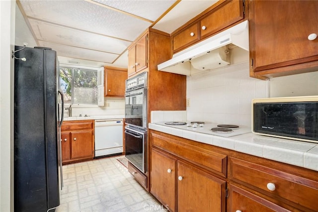 448 Via El Chico, Redondo Beach, CA 90277 - kitchen with white appliances, under cabinet range hood, decorative backsplash, brown cabinetry, and brick patterned flooring
