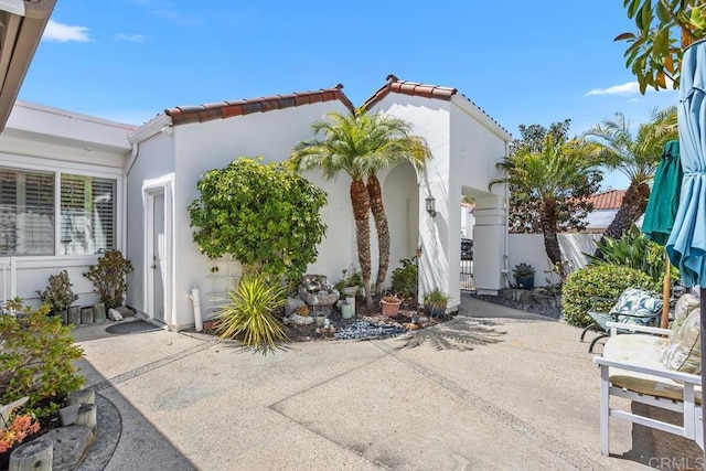 4763 Miletus Way, Oceanside, CA 92056 - view of side of property featuring a patio, stucco siding, and a tile roof