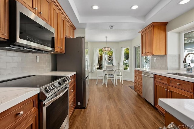 4763 Miletus Way, Oceanside, CA 92056 - kitchen featuring stainless steel appliances, wood finished floors, healthy amount of natural light, a raised ceiling, and recessed lighting