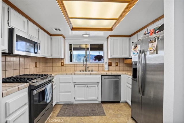27861 Cummings Valley Rd, Tehachapi, CA 93561 - kitchen with stainless steel appliances, white cabinets, tile counters, decorative backsplash, and a raised ceiling