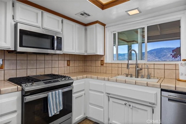27861 Cummings Valley Rd, Tehachapi, CA 93561 - kitchen with appliances with stainless steel finishes, tile counters, white cabinets, and tasteful backsplash