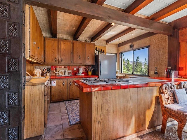 1082 Mountain Canary Dr, South Lake Tahoe, CA 96150 - kitchen featuring tile counters, appliances with stainless steel finishes, brown cabinetry, beam ceiling, and a peninsula