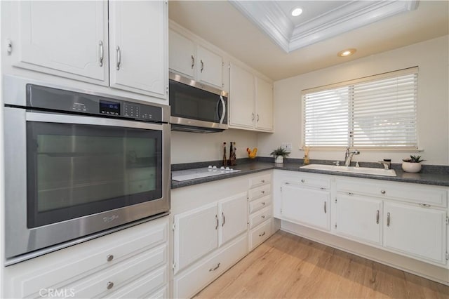 2245 Via Mariposa E Unit D, Laguna Woods, CA 92637 - kitchen with appliances with stainless steel finishes, recessed lighting, dark countertops, light wood-style flooring, and white cabinets