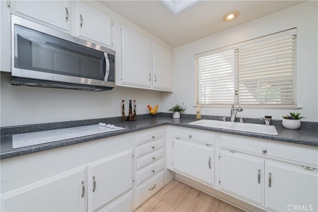 2245 Via Mariposa E Unit D, Laguna Woods, CA 92637 - kitchen with stainless steel microwave, white cabinetry, dark countertops, recessed lighting, and white electric cooktop