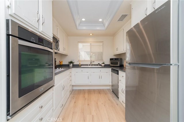 2245 Via Mariposa E Unit D, Laguna Woods, CA 92637 - kitchen with stainless steel appliances, a raised ceiling, ornamental molding, dark countertops, and light wood-style flooring