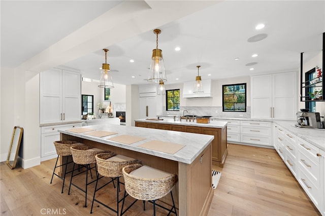 1963 Port Edward Pl, Newport Beach, CA 92660 - kitchen with a kitchen island with sink, backsplash, recessed lighting, light wood-style floors, and a breakfast bar area