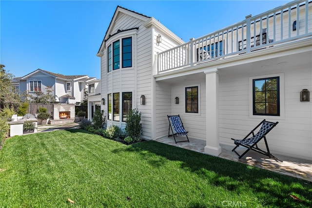 1963 Port Edward Pl, Newport Beach, CA 92660 - rear view of house with a warm lit fireplace, a balcony, a patio area, and a lawn