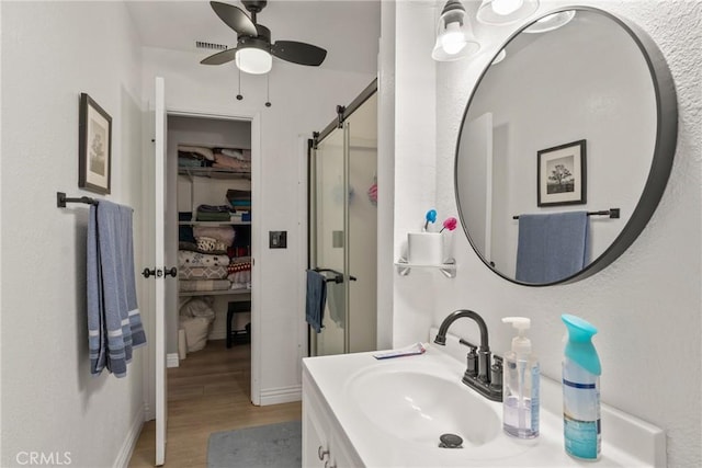 1504 Valaria Dr, Highland, CA 92346 - full bathroom featuring wood finished floors, a shower stall, vanity, ceiling fan, and a spacious closet