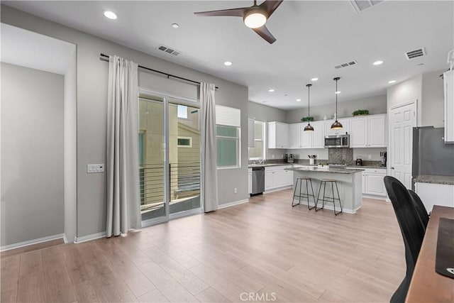 27422 Pioneer Ct, Valencia, CA 91381 - kitchen featuring stainless steel appliances, ceiling fan, a kitchen island, white cabinets, and a breakfast bar area